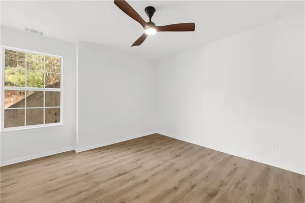 an empty room with wooden floor cabinet and windows