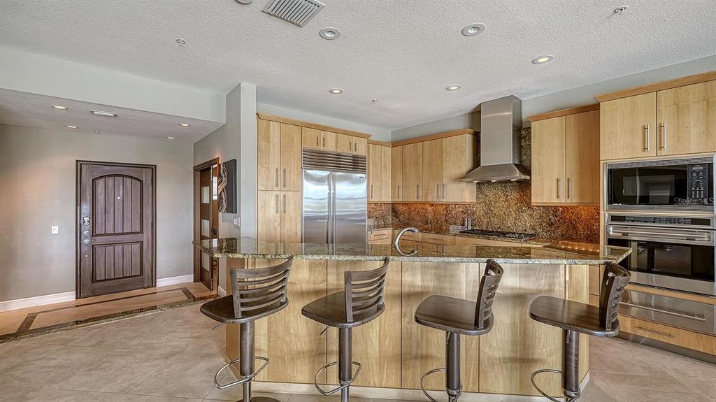 650 Golden Gate Point, Unit 602 Sarasota, FL 34236 - Photo 18 of 50 a kitchen with granite countertop cabinets and chairs