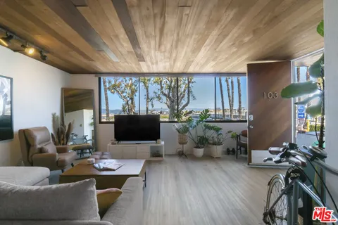 a living room with furniture a flat screen tv and a floor to ceiling window