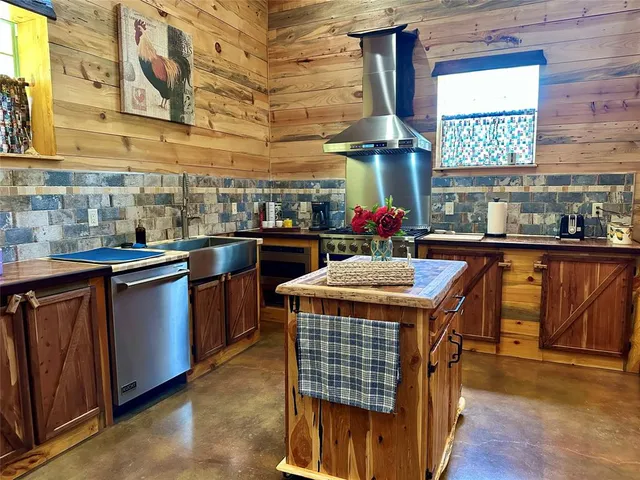 a kitchen with stainless steel appliances granite countertop a stove a sink dishwasher and a dining table with wooden cabinet