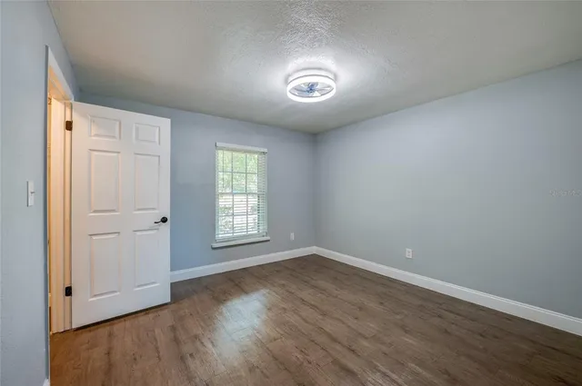 a bed sitting in a spacious bedroom next to a window and a chair