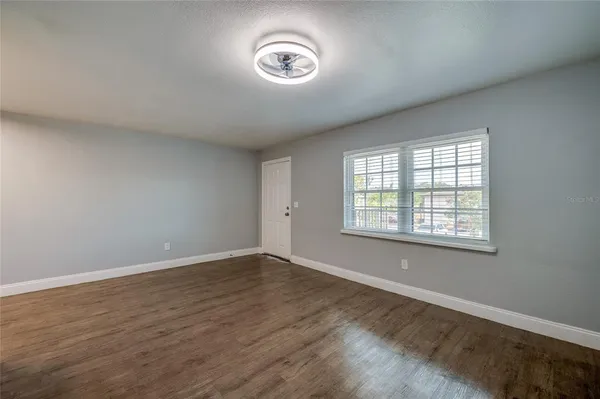 a view of an empty room with wooden floor and a window