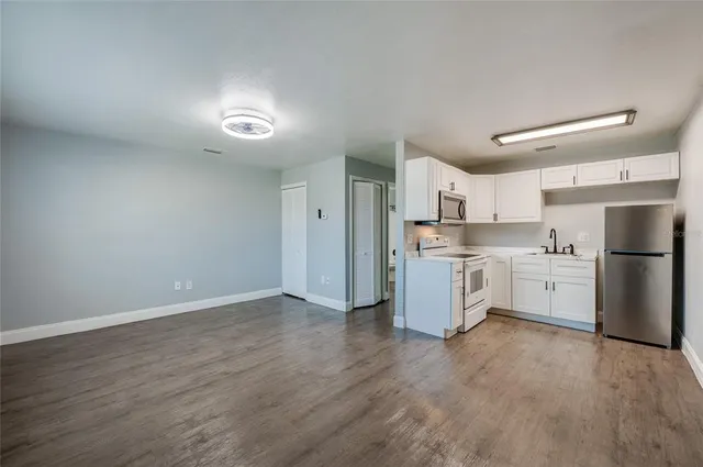 a living room with stainless steel appliances furniture a dining table and chairs
