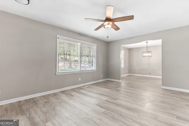 an empty room with wooden floor fan and windows