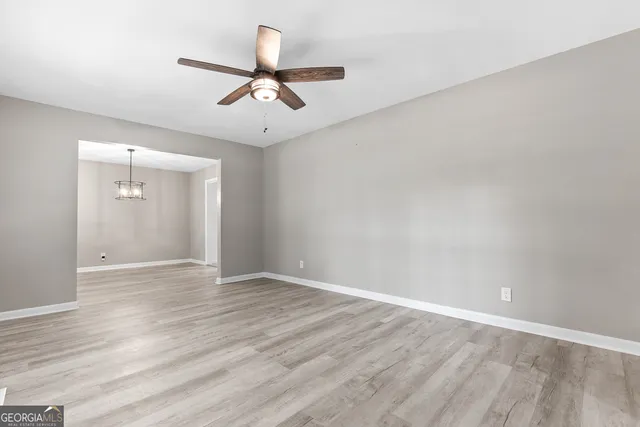 an empty room with wooden floor ceiling fan and windows