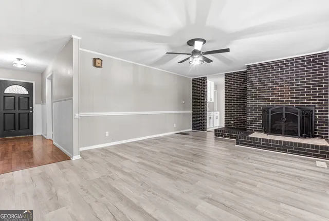 a view of an empty room with wooden floor fireplace and a window
