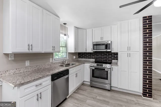 a kitchen with granite countertop white cabinets and appliances