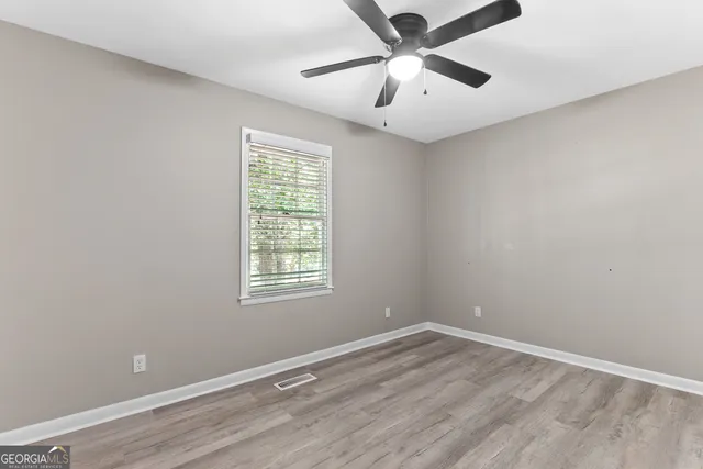 an empty room with a window and a fan