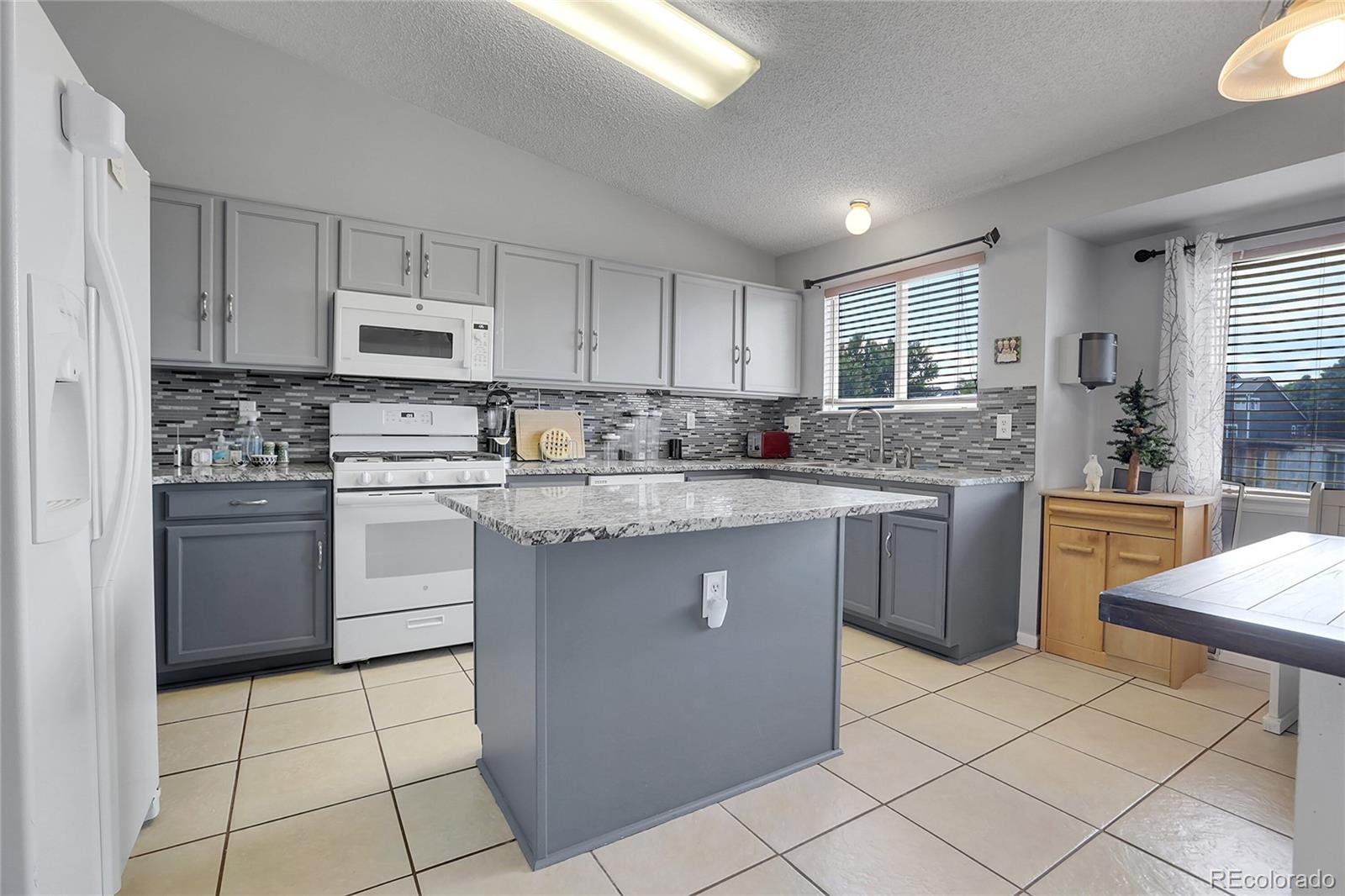 a kitchen with kitchen island granite countertop a sink a counter top space appliances and cabinets