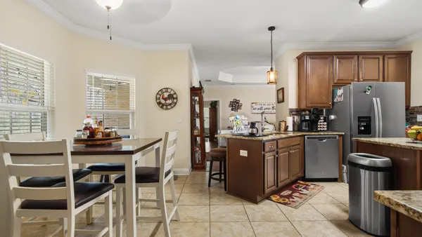 a kitchen with stainless steel appliances granite countertop a stove refrigerator and chairs