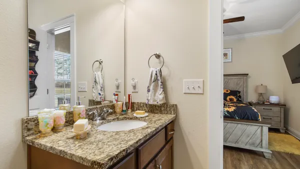 a bathroom with sinks granite countertop and a view of living room