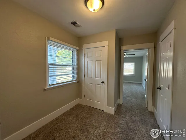 a view of an empty room with closet and a window