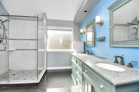 a bathroom with a granite countertop sink a mirror and a shower