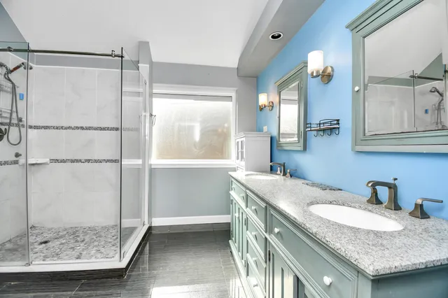 a bathroom with a granite countertop sink a mirror and a shower