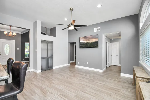 a view of a livingroom with a chandelier fan and windows