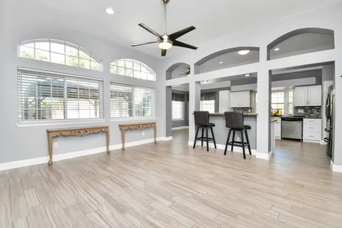 a dining room with wooden floor a chandelier a glass table and chairs