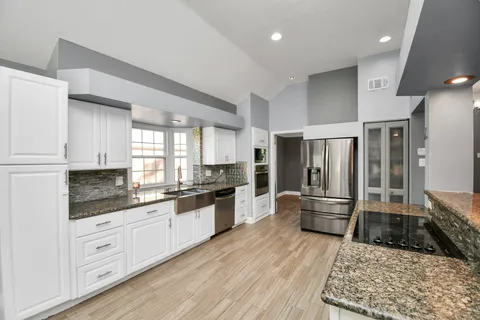 a large kitchen with cabinets wooden floor and stainless steel appliances