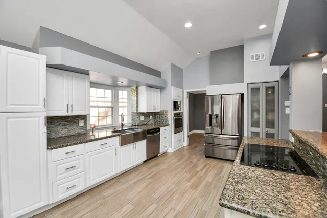 a large kitchen with cabinets wooden floor and stainless steel appliances