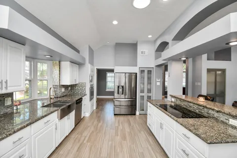 a large kitchen with stainless steel appliances a lot of counter space and wooden floor