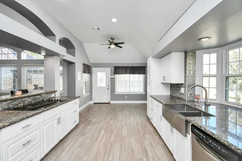 a large kitchen with stainless steel appliances granite countertop a lot of counter space and wooden floors
