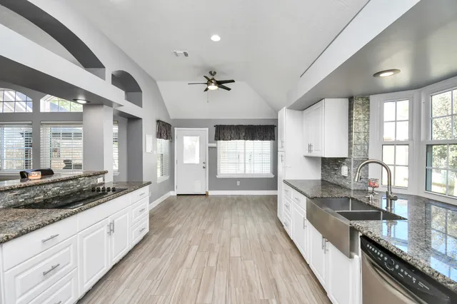 a large kitchen with stainless steel appliances granite countertop a lot of counter space and wooden floors