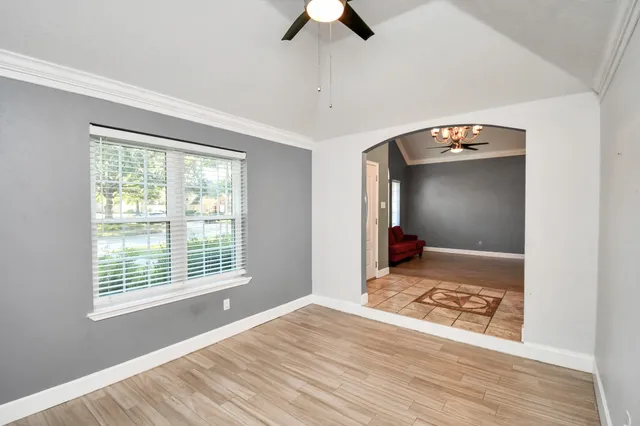 a view of an empty room with window and wooden floor
