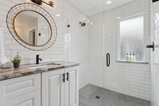 a bathroom with a granite countertop sink a mirror and a shower