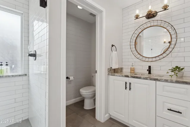 a bathroom with a granite countertop toilet a sink and a mirror