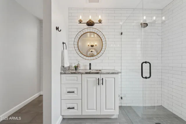 a bathroom with a granite countertop shower a sink and a mirror