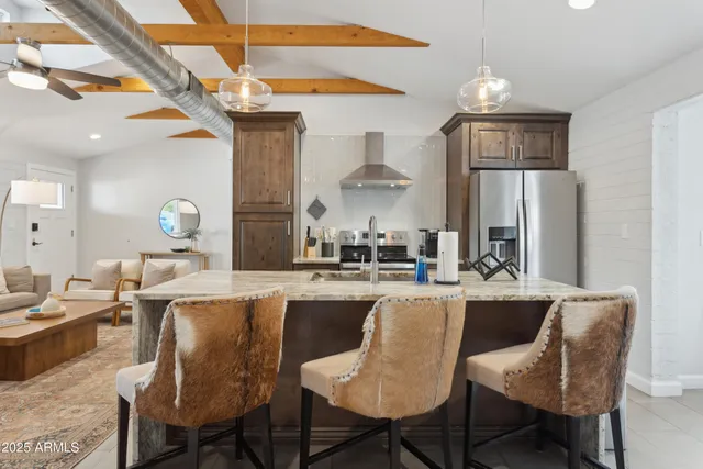 a kitchen with granite countertop a sink cabinets a refrigerator and chairs