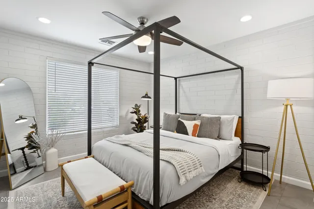 a bedroom with a bed a lamp and a large window