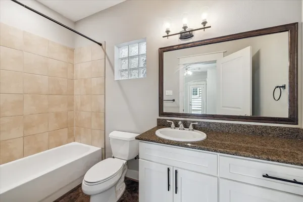a bathroom with a granite countertop sink toilet mirror and bathtub