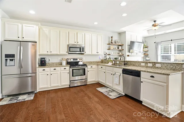 a kitchen with stainless steel appliances granite countertop a refrigerator sink and white cabinets