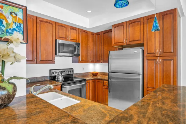 a kitchen with granite countertop stainless steel appliances a refrigerator a stove top oven and a sink