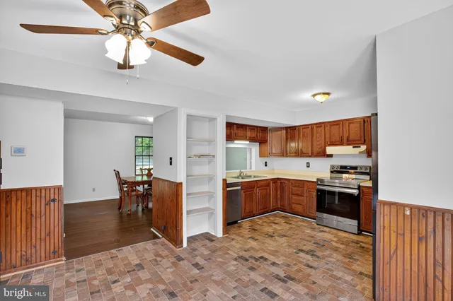 a kitchen with stainless steel appliances granite countertop a stove top oven a sink a dining table and chairs with wooden floor