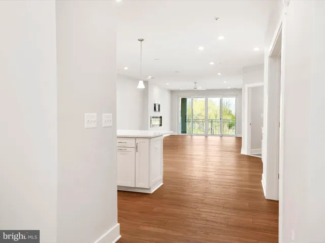 a large white kitchen with kitchen island a sink wooden floor and stainless steel appliances