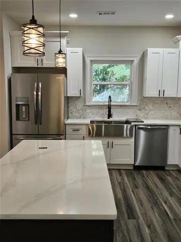 a room with kitchen island a sink stainless steel appliances and cabinets