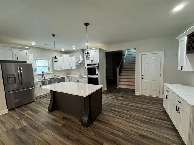 a kitchen with stainless steel appliances a sink a stove a refrigerator and cabinets
