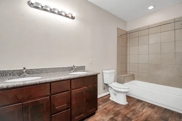 a bathroom with a granite countertop sink a toilet and bathtub