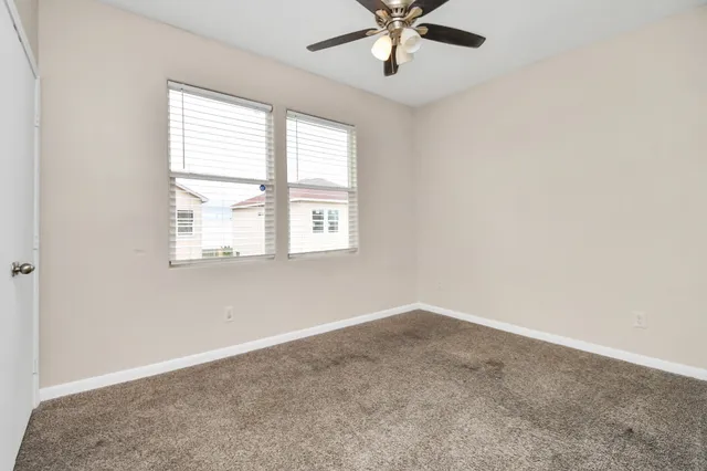 an empty room with a window and a fan