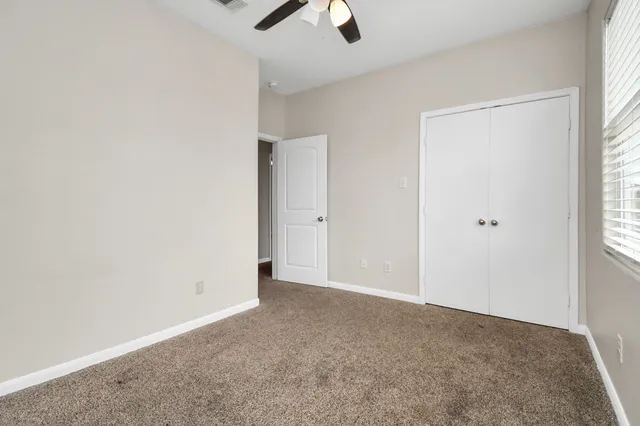 an empty room with ceiling fan and window