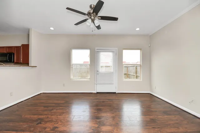 a view of an empty room with a window and wooden floor