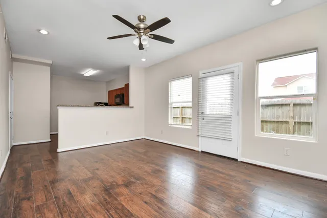 an empty room with wooden floor and windows