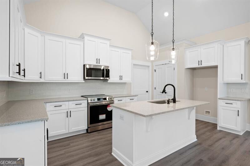 150 Doris Path Dallas, GA 30157 - Photo 13 of 36 a kitchen with stainless steel appliances granite countertop a sink stove a refrigerator and white cabinets with wooden floor