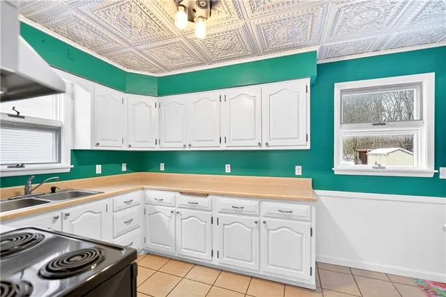 a kitchen with white cabinets a sink a stove and a wooden floors