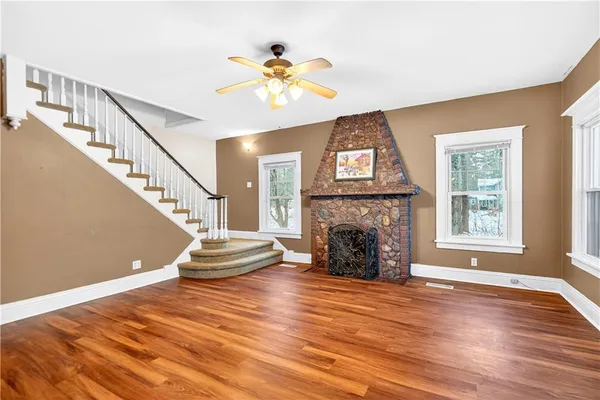 a view of an empty room with wooden floor fireplace and a window