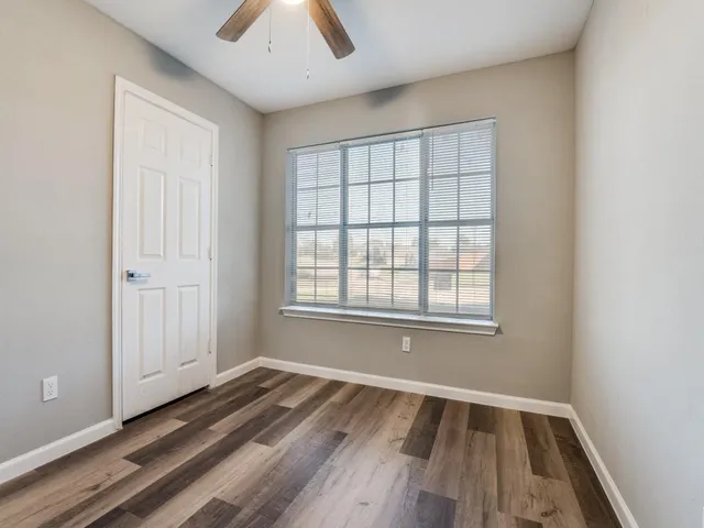 an empty room with wooden floor and windows