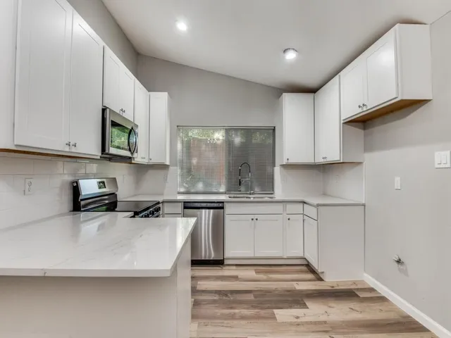 a kitchen with stainless steel appliances granite countertop a sink a stove and a microwave