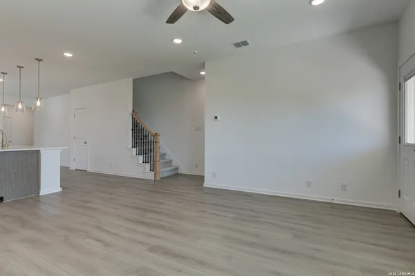 an empty room with a chandelier fan and windows