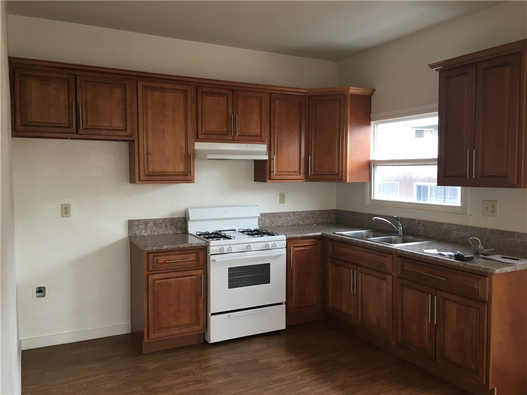 1043 Stanley Avenue Long Beach, CA 90804 - Photo 9 of 16 a kitchen with stainless steel appliances granite countertop wooden cabinets stove top oven and sink
